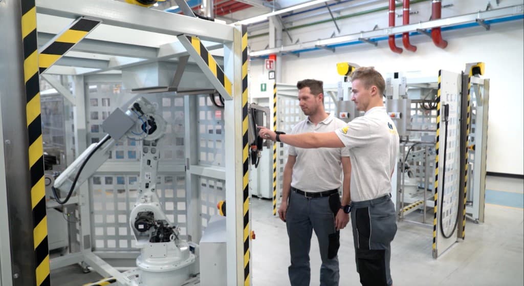 Technicians operating an industrial robotic arm on the factory floor